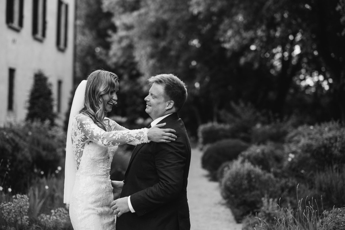 Ellie and Chad embracing in front of the villa, black and white