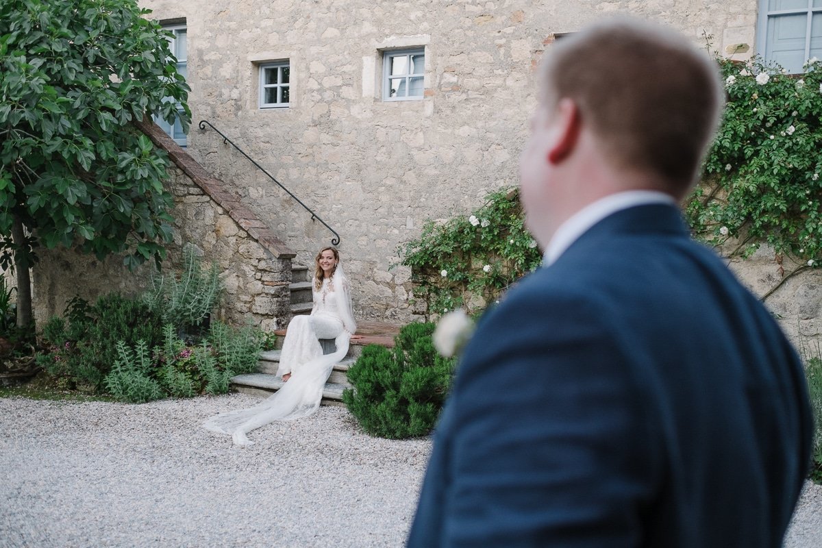 Bride on the stone steps of the villa, groom in the foreground