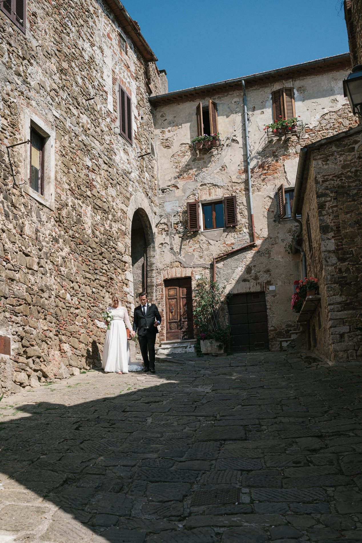 Bride and Groom walking in the ancient town of Montemerano in Maremma