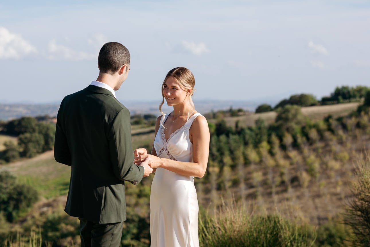 Bride and groom facing each other in the countryside of Le Marche