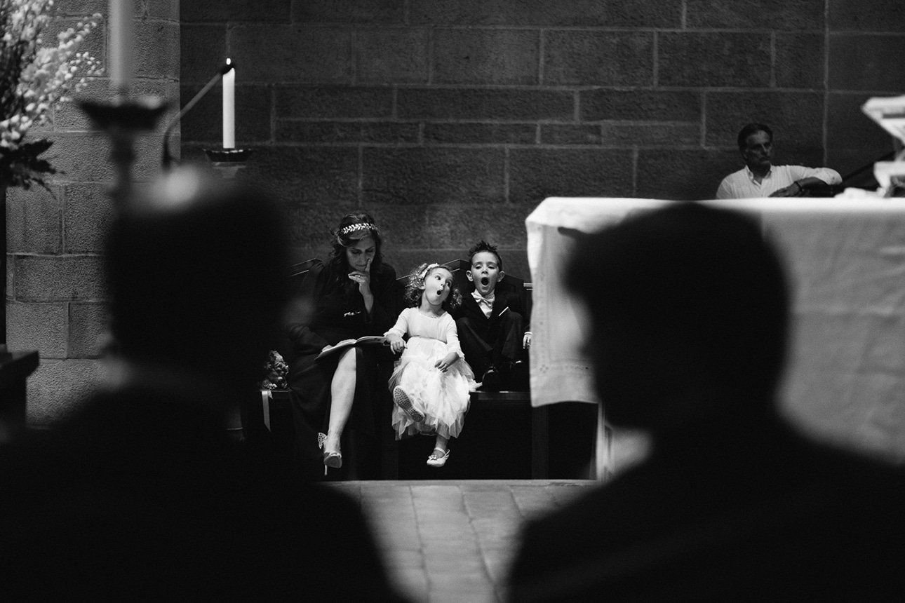 Little kids sitting during the ceremony, seen past guests in silhouette