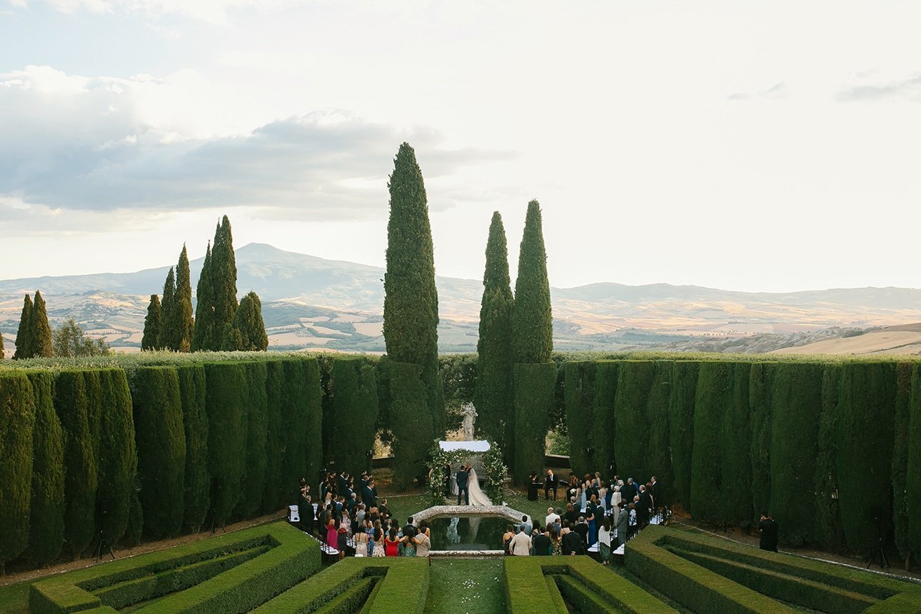 Outdoor wedding ceremony in an Italian garden with cypresses and Val d'Orcia hills