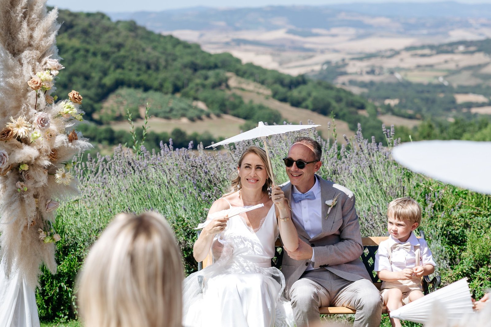 bride and groom sitting for the ceremony with the Val d'Orcia behind