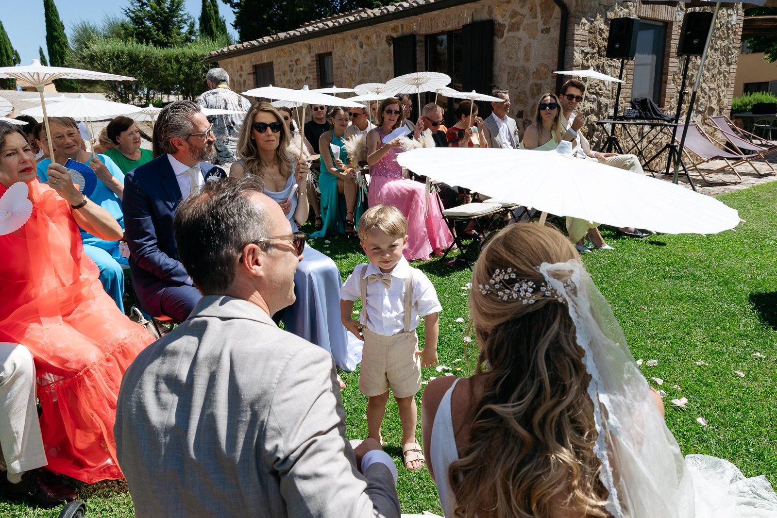 Guests under the parasols watching the ceremony