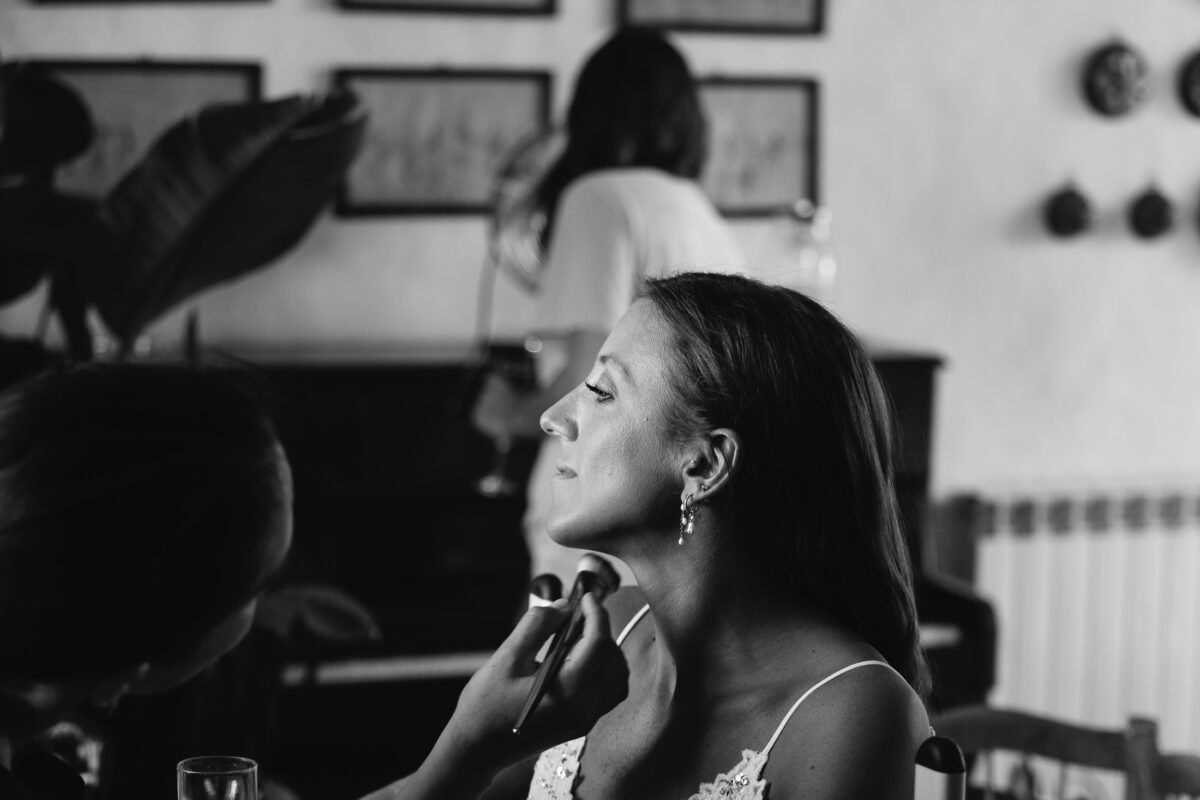 Bride having her make-up done by the window, black and white