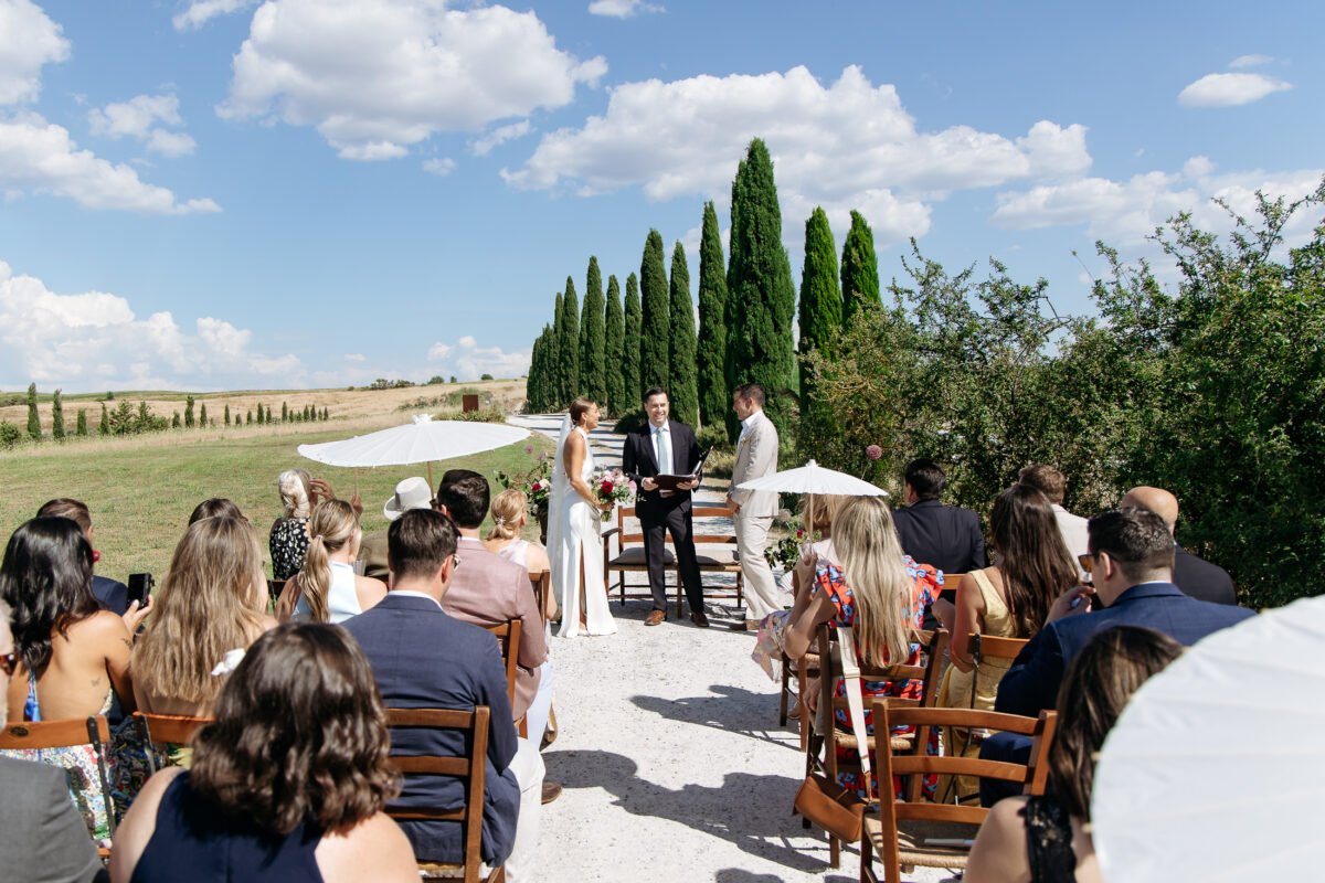 Guests seated for the ceremony with cypresses in the background