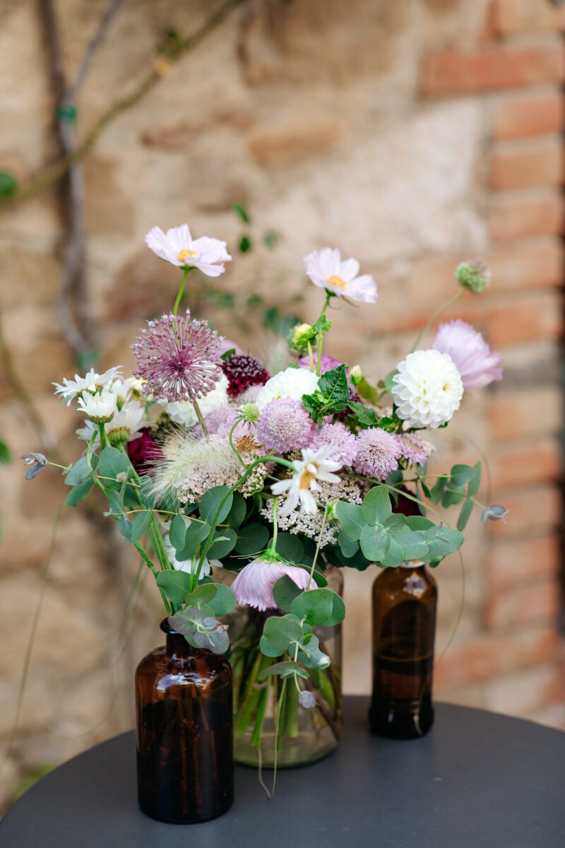 Pink flowers in a vase against an old stone wall