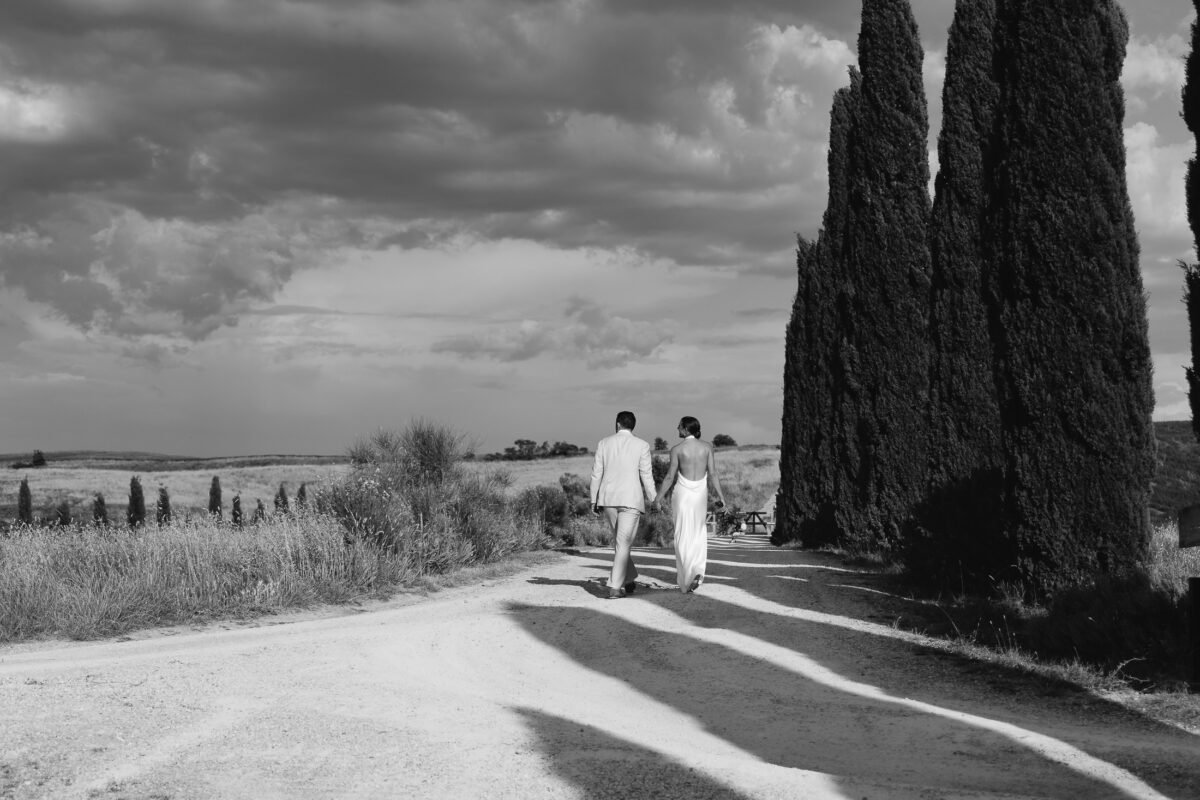 Bride and groom walking along a cypress road, black and white