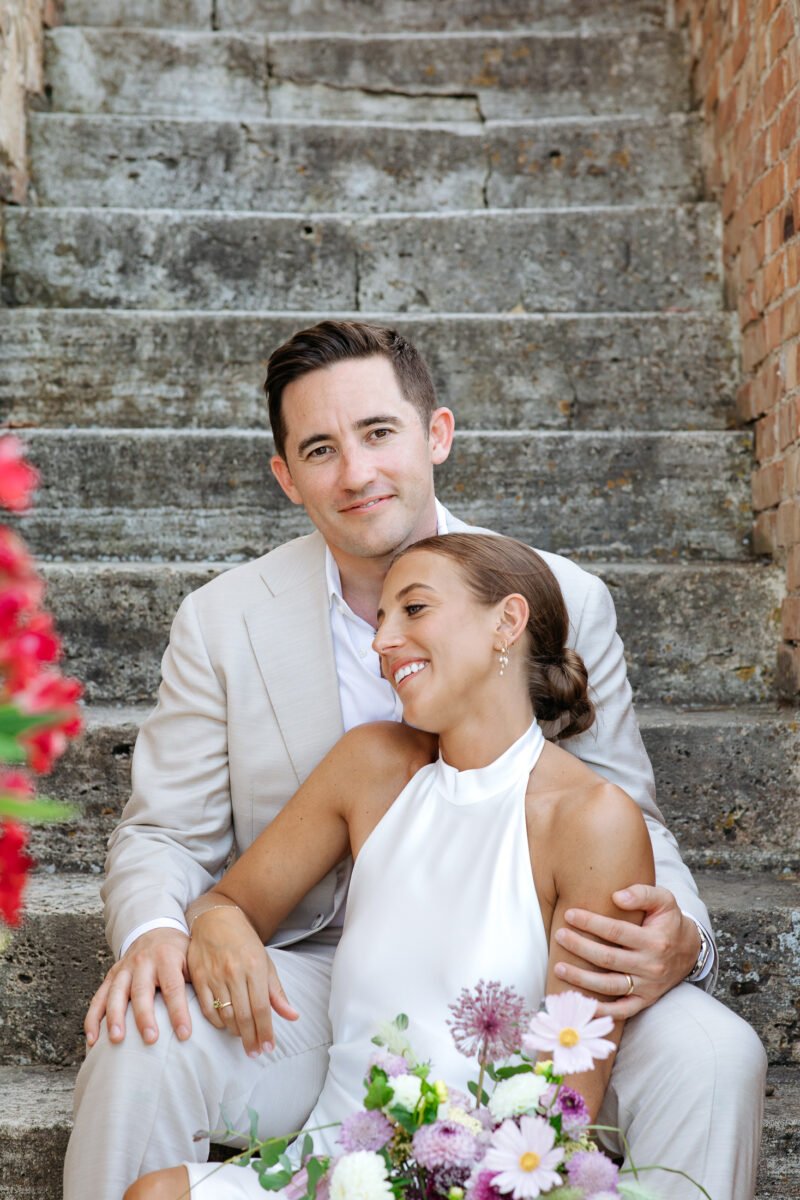 Bride and groom sitting on the stone steps of Il Rigo