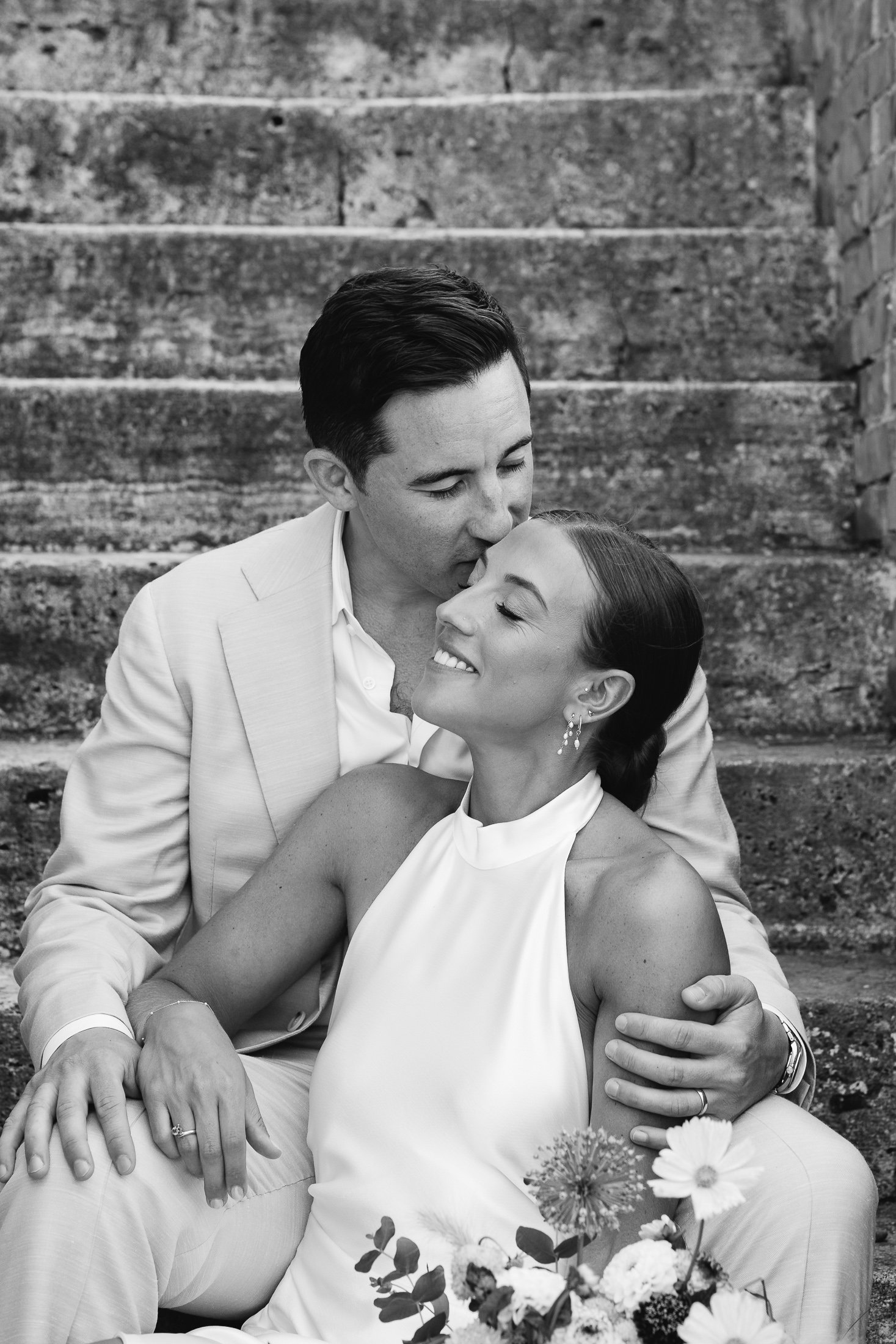Nicole and James kissing on the stone steps at Il Rigo, black and white portrait
