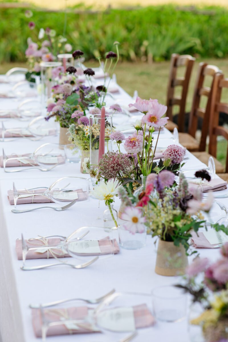Long imperial table on the lawn with simple colourful flowers