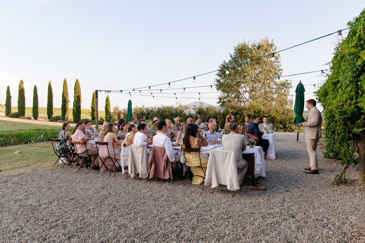 Dinner tables on the lawn at sunset under string lights