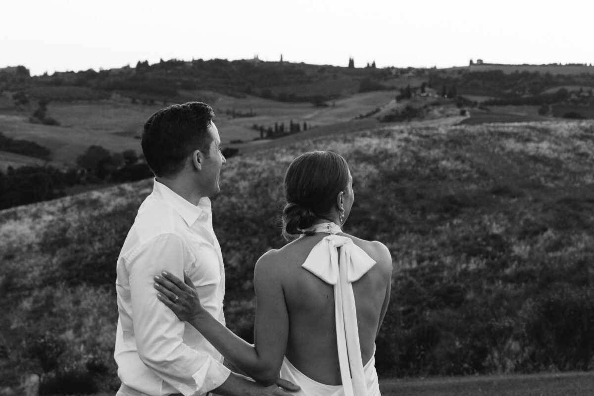 Couple sitting together looking over the hills at dusk