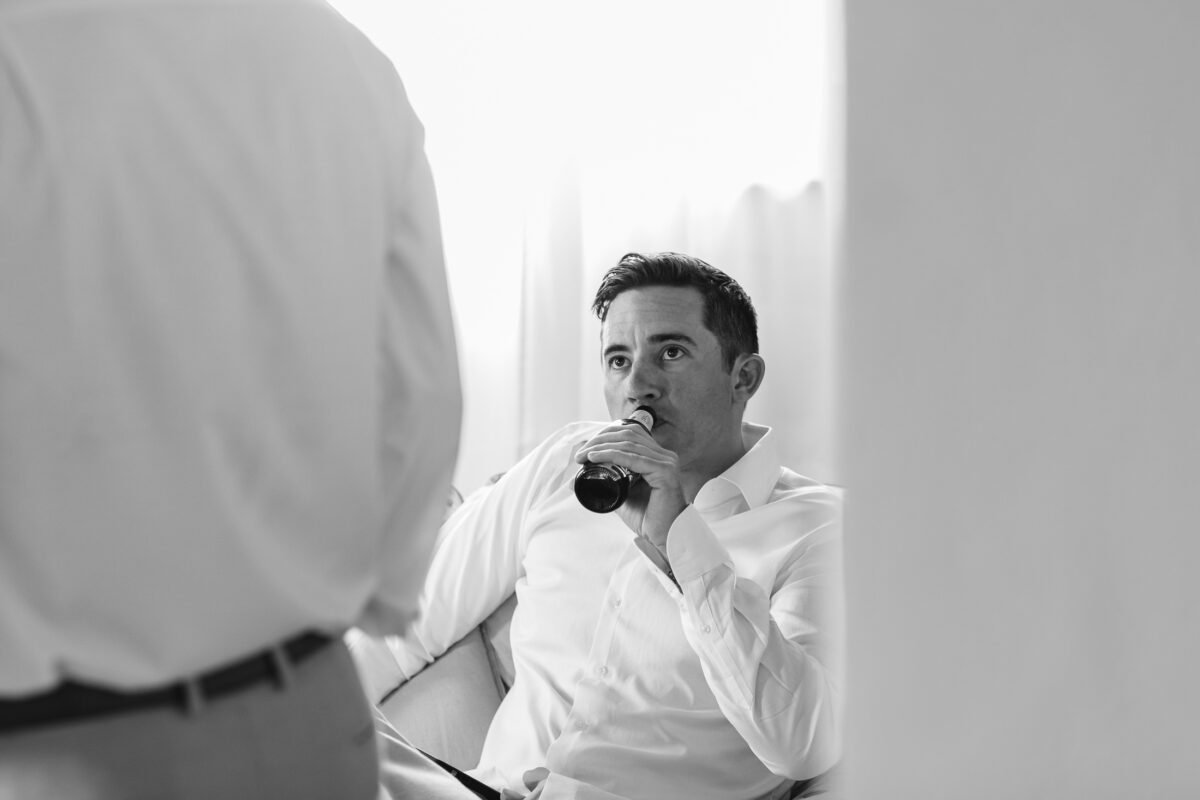 Groom drinking a beer in the window light